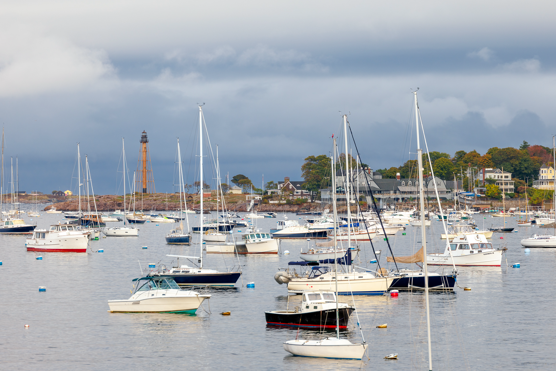 Marblehead Harbor filled with sailboats, lighthouse in the distance